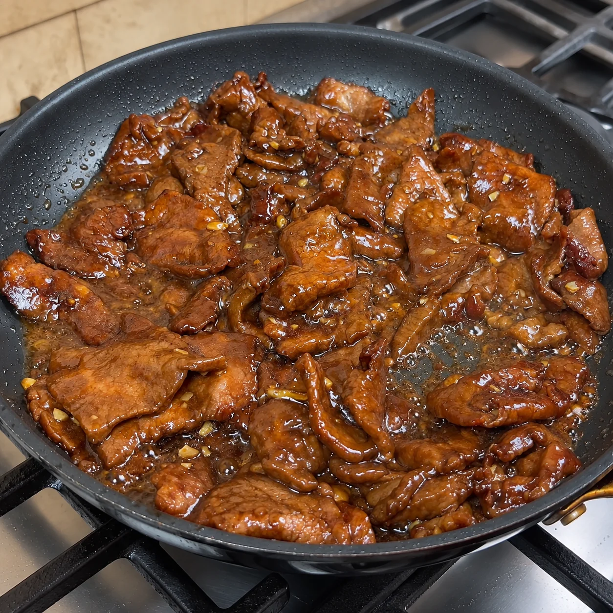 Beef and onion stir fry cooking in a pan with green onion