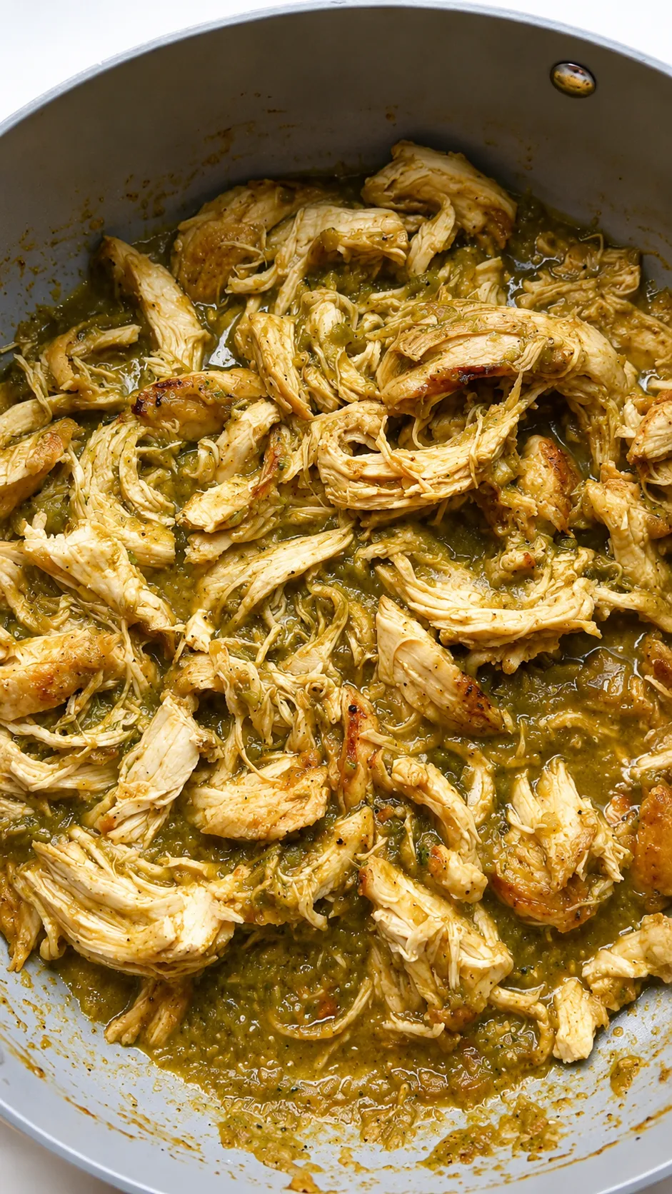 Shredded salsa verde chicken in a pan