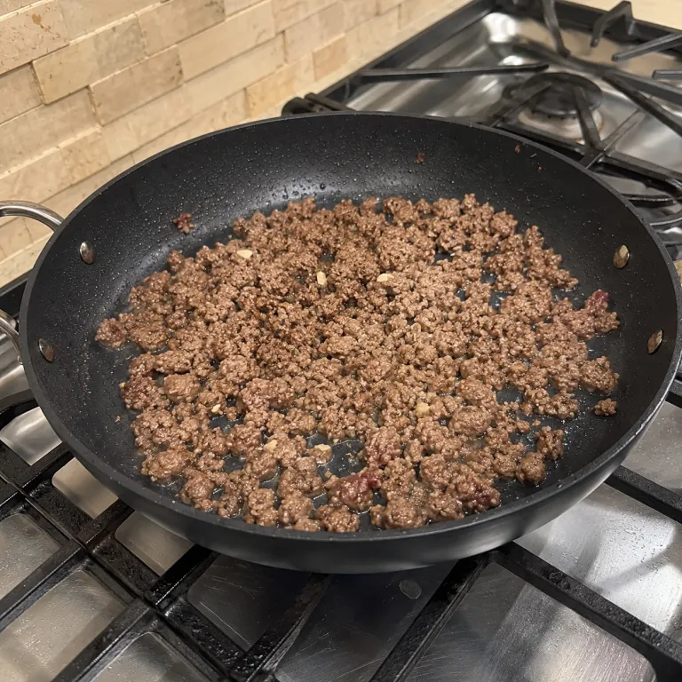 Ground beef browning in a skillet on the stove