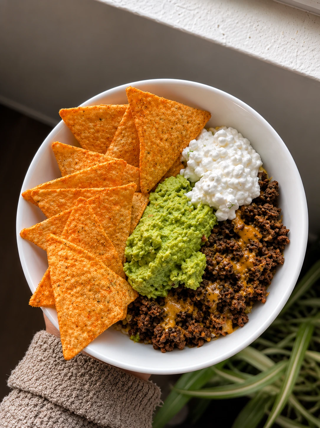 Taco-style ground beef bowl with tortilla chips, guacamole, and cottage cheese
