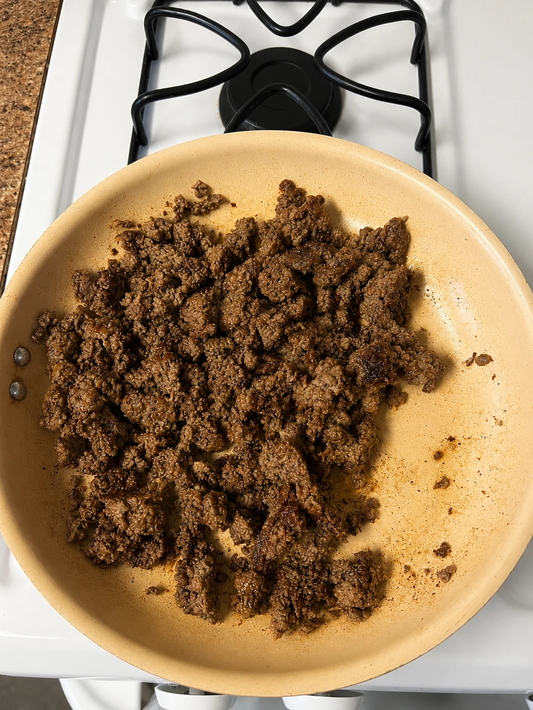 Ground beef browning in a nonstick skillet on the stove