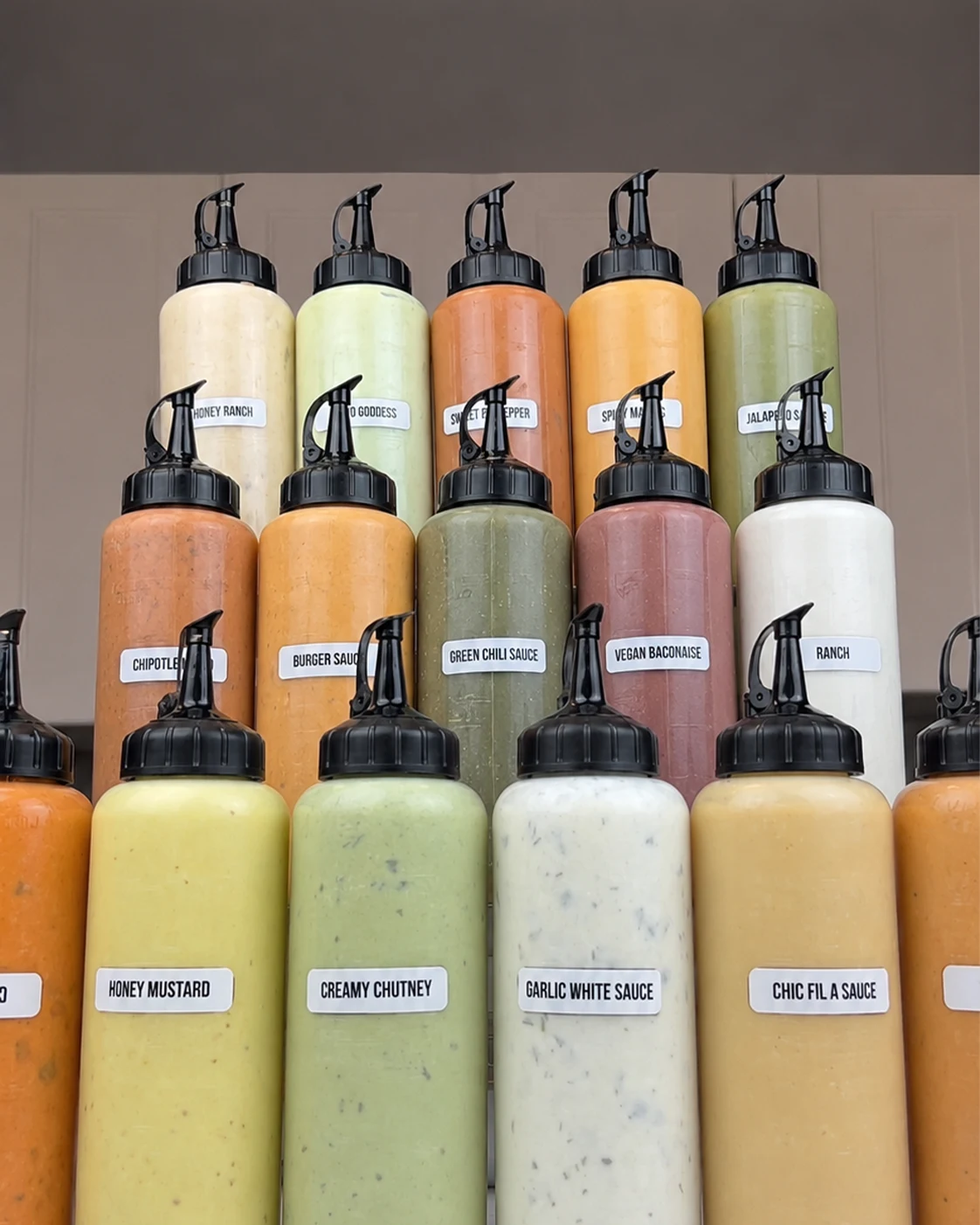 Labeled homemade sauce squeeze bottles including ranch, chipotle, and honey mustard